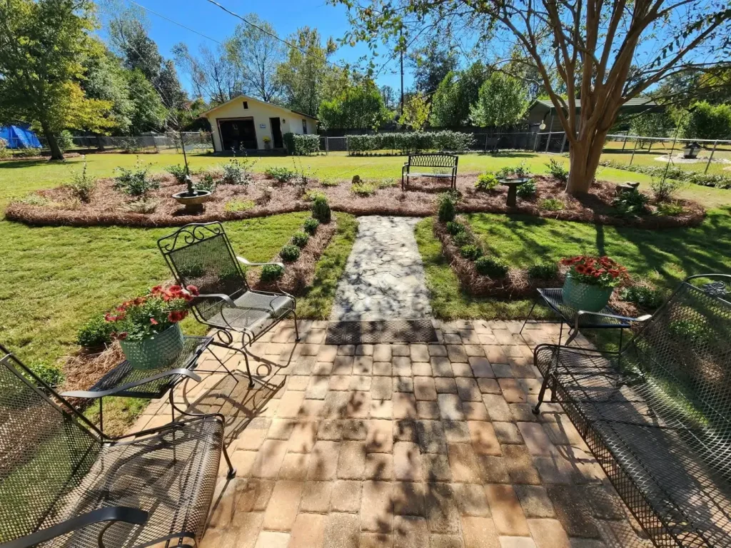 Landscaped backyard patio, flower beds, and stone path by Premium Petals in Dothan, AL