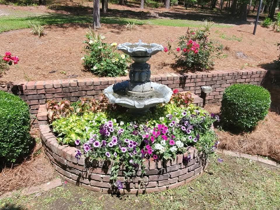Landscape design and installation in Dothan, AL: a flower bed with a stone fountain by Premium Petals